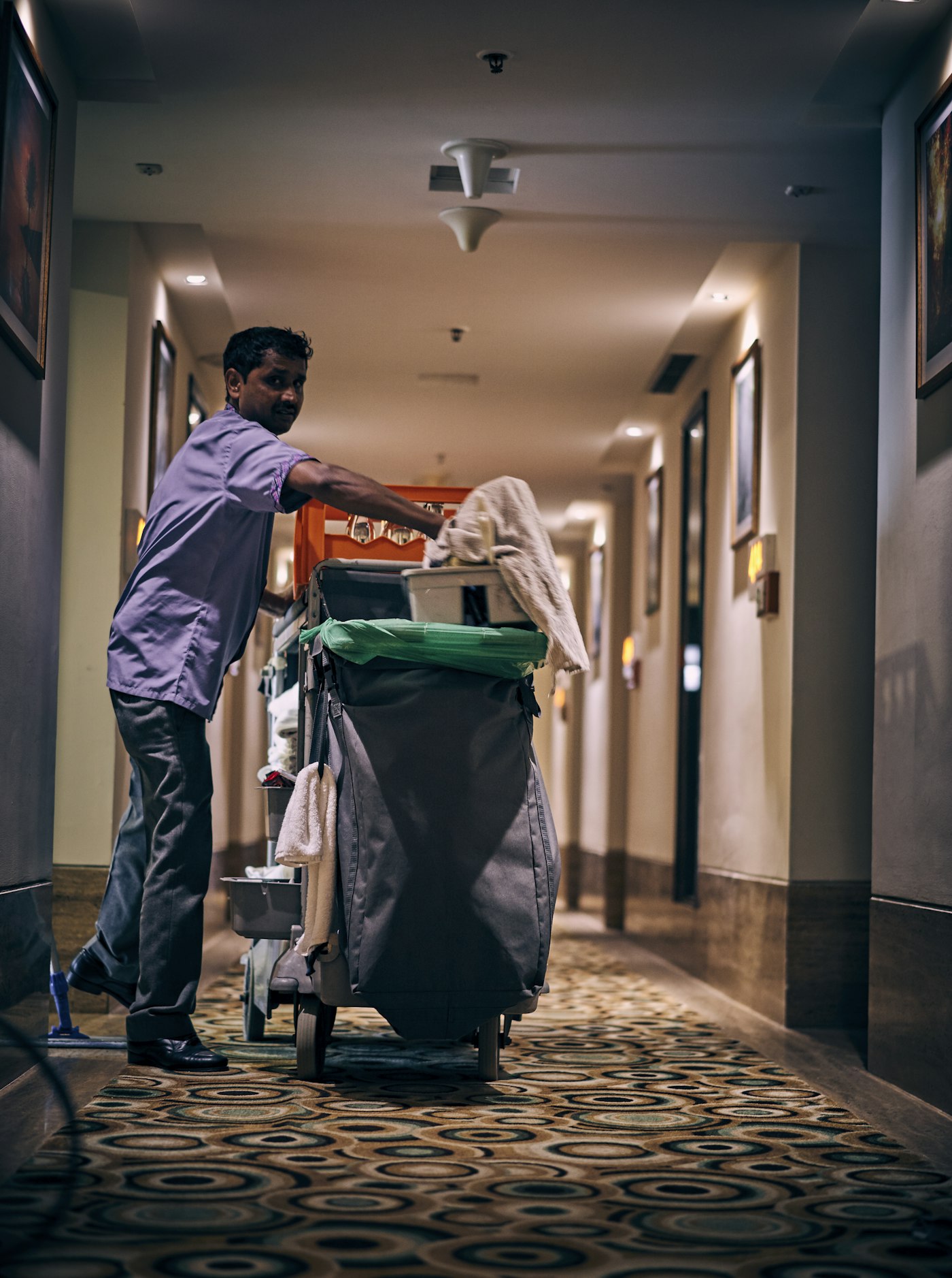 Cleaner with trolley in a building corridor